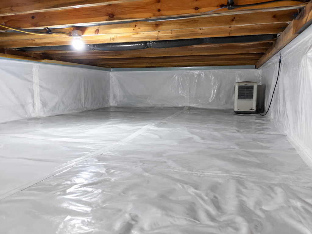 Crawl space in a Grand Rapids home with a sealed white vapor barrier and dehumidifier after encapsulation